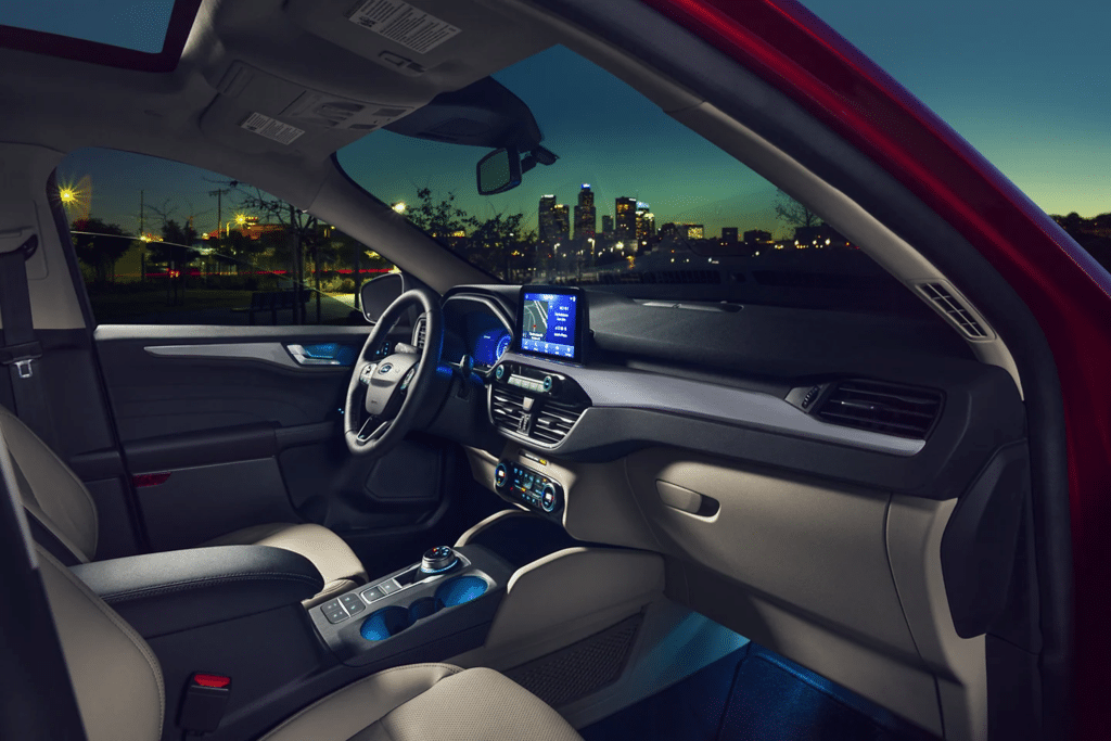Interior view of a modern SUV showcasing the dashboard, steering wheel, and advanced infotainment system, illuminated against a city skyline at dusk. Features include leather seats, climate control, and ambient lighting.