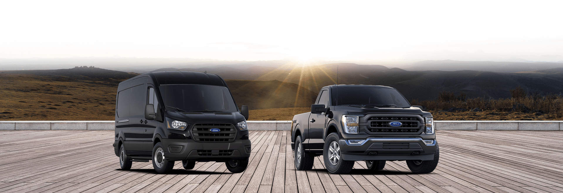 Black Ford Transit van and F-150 truck parked on a wooden deck with mountains in the background, showcasing their rugged design and versatility.